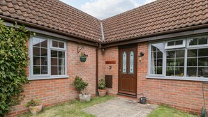 A brick house with a tiled roof, a front door, and potted plants.