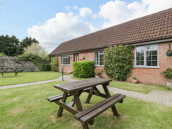 A brick building with a tiled roof, a picnic table, and a stone wall. - Owls Retreat (Weston-super-Mare)