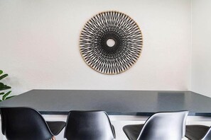 A modern dining area with a round wall decoration, a dark table, and black chairs.