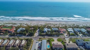 An aerial view of a coastal residential area with houses, a beach, and a clear sky. - 400 South - Unit D (Cocoa Beach)