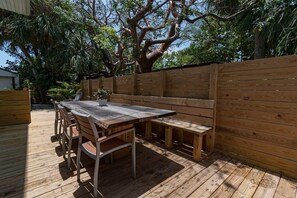 A wooden deck with a table and benches, surrounded by a wooden fence and trees. - 400 South - Unit D (Cocoa Beach)
