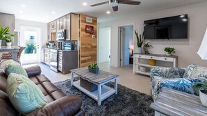 A modern living room with a sofa, coffee table, and TV. - 400 South - Unit C (Cocoa Beach)
