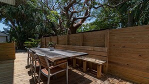 A wooden deck with a table and benches, surrounded by a wooden fence and trees. - 400 South - Unit C (Cocoa Beach)