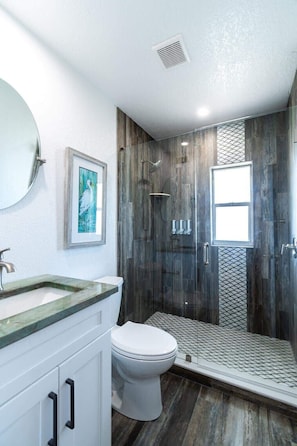 A modern bathroom with a shower, toilet, and sink.