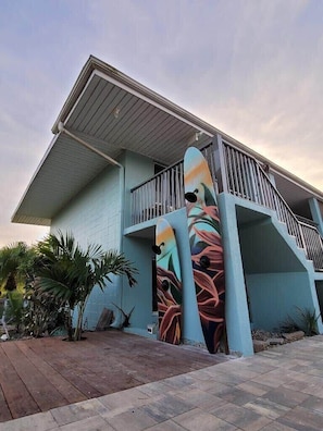 A building with a light blue exterior, a balcony, and a colorful mural on the side.