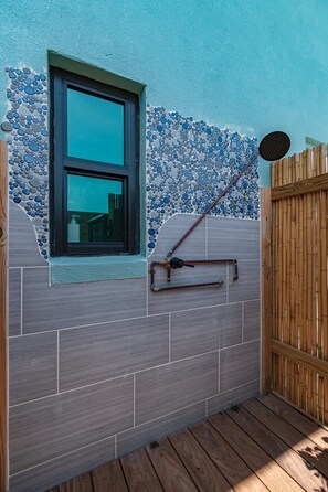 Exterior wall features a unique blend of textured tiles and pebbles, with an entrance through a window.