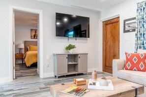 A modern living room with a flat-screen TV, a wooden coffee table, a sofa, and a door leading to another room. - 400 South - Unit B (Cocoa Beach)