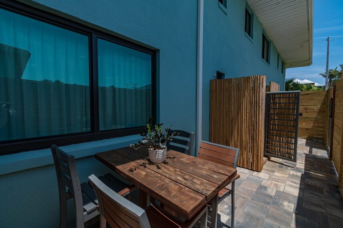 Outdoor patio with a wooden dining table and seating for four in a private fenced area.