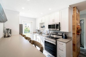 A modern kitchen with white cabinets, stainless steel appliances, and a large island with seating.