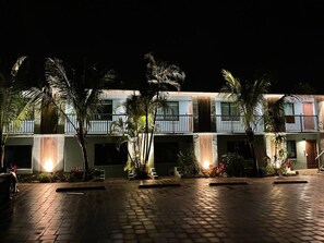 A hotel with a courtyard, palm trees, and a waterfall feature.