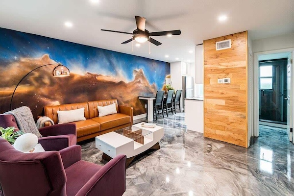 Modern living room with a space-themed mural and polished concrete floors.