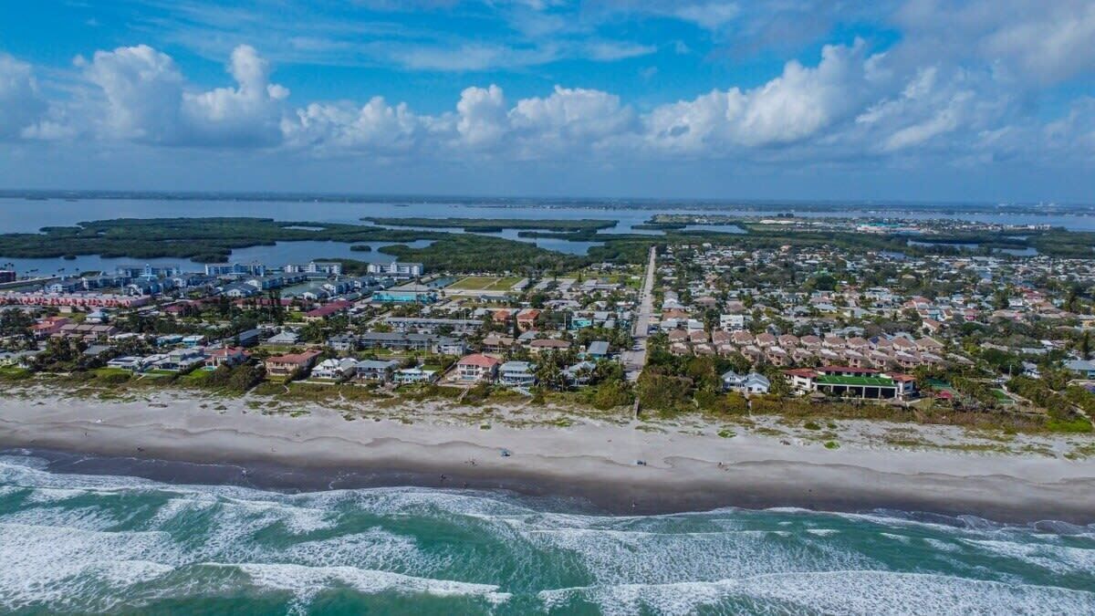 Aerial view of the beachfront neighborhood with ocean waves and coastal homes.