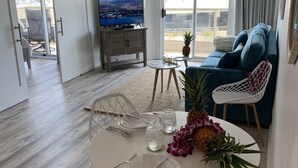 Un salon moderne comprenant un coin repas, un grand téléviseur et une vue sur l’extérieur.