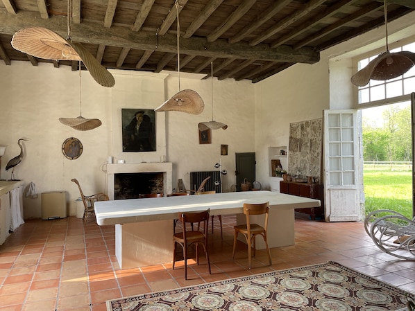 A rustic interior with a fireplace, wooden ceiling beams, and a dining area with chairs.