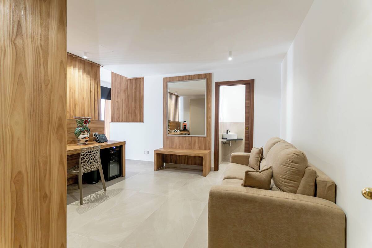 Un salon moderne avec un bureau en bois, un canapé et un grand miroir.