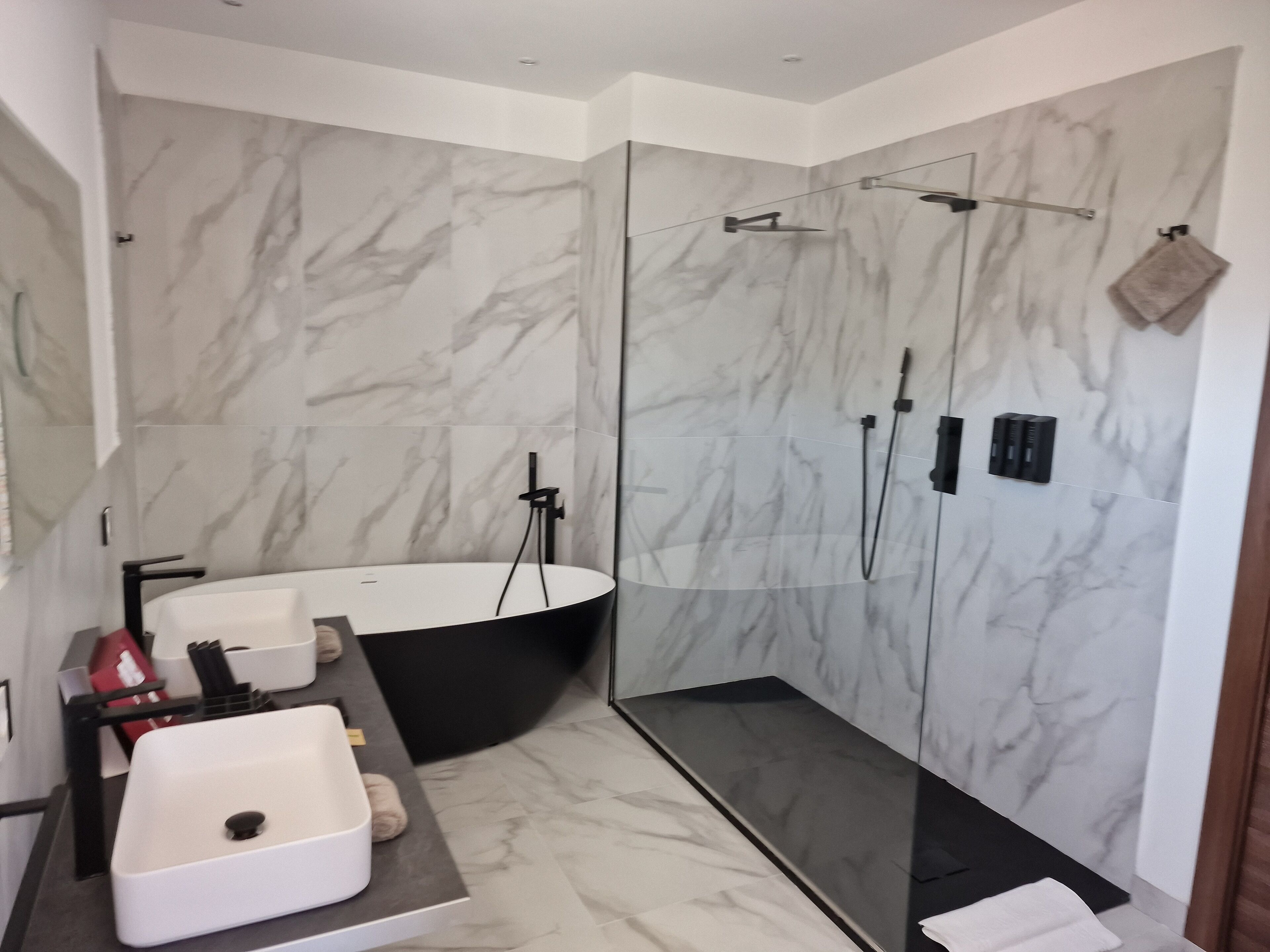 A modern bathroom with a freestanding bathtub, a glass-enclosed shower, and a vanity with a sink and towel rack.