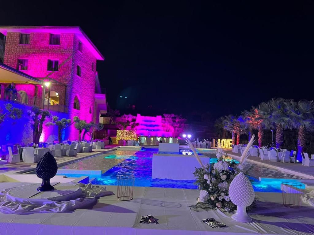Un hall d’hôtel doté d’une piscine, d’espaces aménagés pour se détendre et d’un comptoir d’accueil.