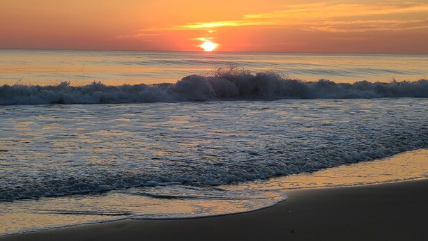 A beach scene with waves and a sunset. - OBX NEW WATERFRONT DESIGNER HOME WITH DOCK. GORGEOUS AND COMFY INSIDE AND OUT! (Kill Devil Hills)