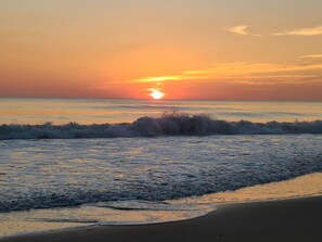A beach scene with waves and a sunset.