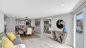 En rummelig opholdsstue med sofa, spisebord og stort vindue.