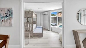 Et soveværelse med køjeseng, udsigt til en pool og en hvid væg med et rundt spejl.