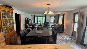 A dining area with a wooden table, chairs, and a chandelier. - Sailors Delight Back Cottage (Greenbush)