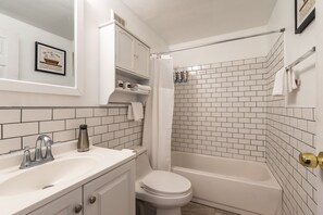 A bathroom with a white sink, toilet, and bathtub. There is a shower curtain, a framed picture on the wall, and a towel rack. - 🏰Warren Castle🏰 - Breathtaking Views of Pittsburgh 💙 (Pittsburgh)