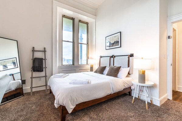 A neatly made bed with white linens, a wooden headboard, and two bedside lamps. - 🏰Warren Castle🏰 - Breathtaking Views of Pittsburgh 💙 (Pittsburgh)
