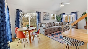A spacious living area with a wooden dining table, red chairs, a sofa, and a staircase. - The Red Lodge - Unique Gem Near Lakes with Game Room and Hot Tub! (Elkhorn)