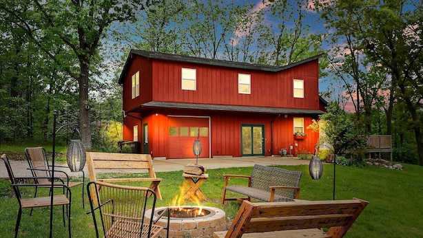 A two-story red house with a fire pit and outdoor seating. - The Red Lodge - Unique Gem Near Lakes with Game Room and Hot Tub! (Elkhorn)
