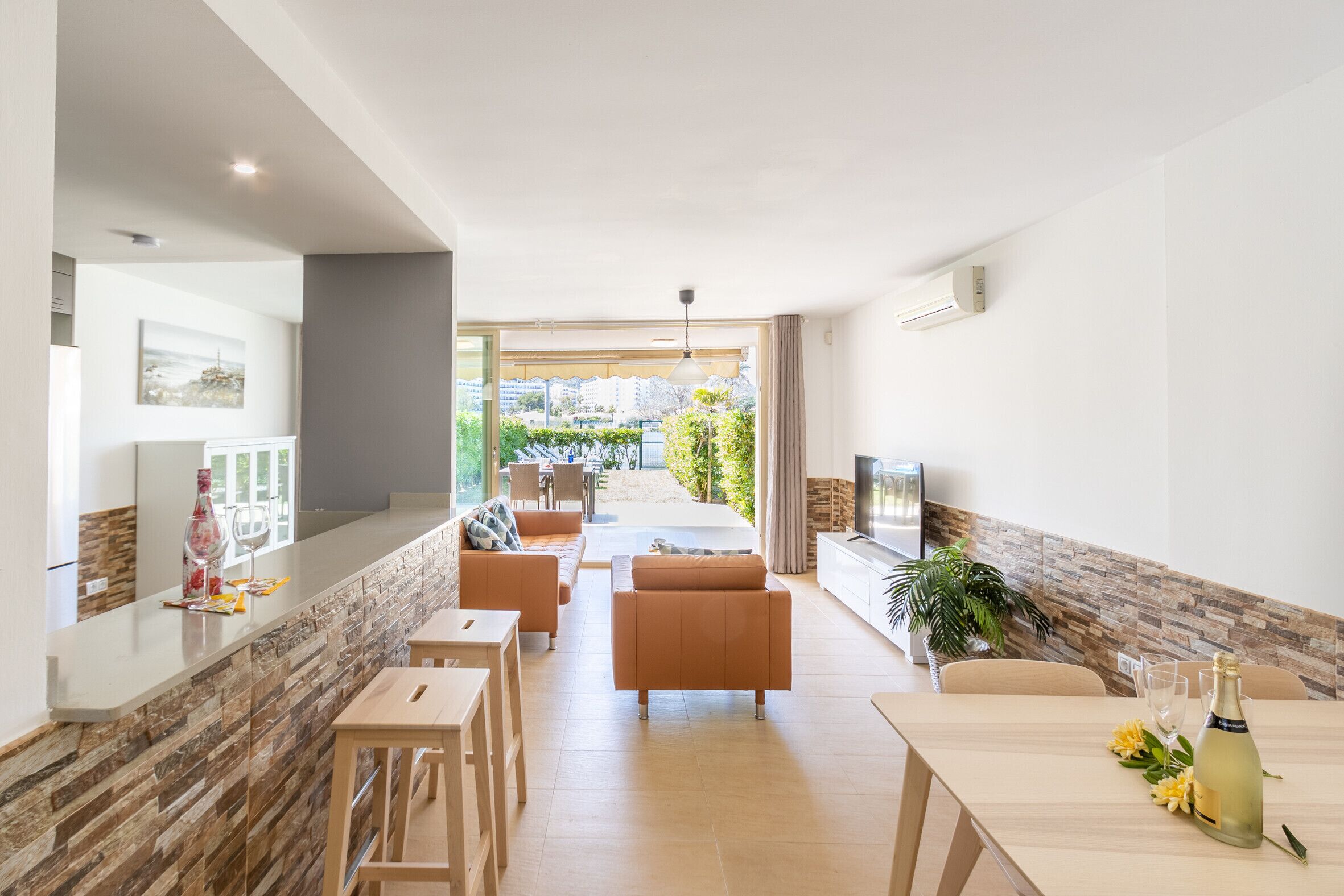 Un saló modern amb zona de cuina, taula de dinar i finestra gran que ofereix vistes a l'exterior.