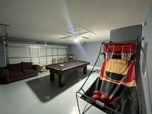 Une pièce équipée d’une table de billard, d’un canapé et d’un panier de basket.