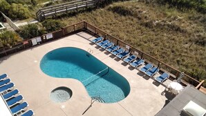Piscina con sedie blu e vasca idromassaggio, circondata da un pontile in legno.