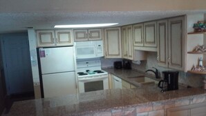 Una cucina dotata di frigorifero, fornello, microonde e un piano di lavoro in granito.