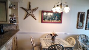 Zona pranzo con decorazione a stella marina sul muro, una veduta marina incorniciata e un lampadario.