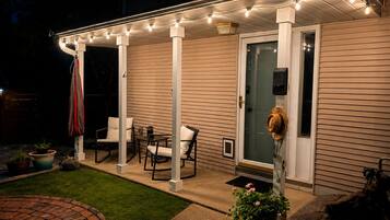 A covered patio area with outdoor seating, a door with a glass panel, and string lights.