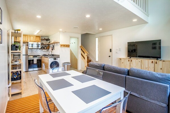 A compact living space with a kitchenette, a sofa, a TV, and a staircase.