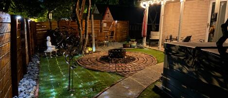 A backyard with a fire pit, seating area, and a wooden fence.