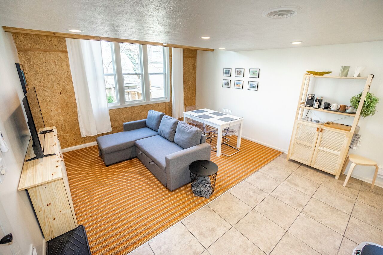 A modern living room with a sectional sofa, a dining table, and a built-in bookshelf.
