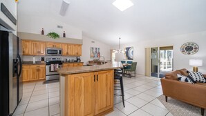 Een moderne keuken met houten kasten, een centraal eiland en een zithoek met een bank en tafel.