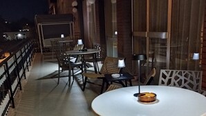 An outdoor dining area with round tables and chairs, a railing, and a view of the night sky. - Hotel Luca (Rimini)