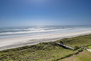 A coastal landscape with a beach, a walking path, and a person running. - Sand Dollar 507 Penthouse Paradise (St. Augustine)