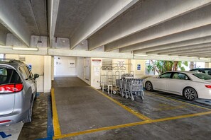 A parking garage with cars, shopping carts, and a wheelchair-accessible sign.