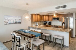 A modern kitchen with wooden cabinets, stainless steel appliances, and a granite countertop.