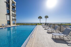 A swimming pool with lounge chairs and a view of the ocean. - Sand Dollar 507 Penthouse Paradise (St. Augustine)