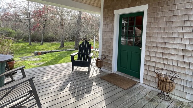 Une terrasse en bois avec une porte verte, une chaise et une petite table.