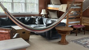 Une pièce chaleureuse avec un hamac, des lits superposés, un canapé et une table à manger.
