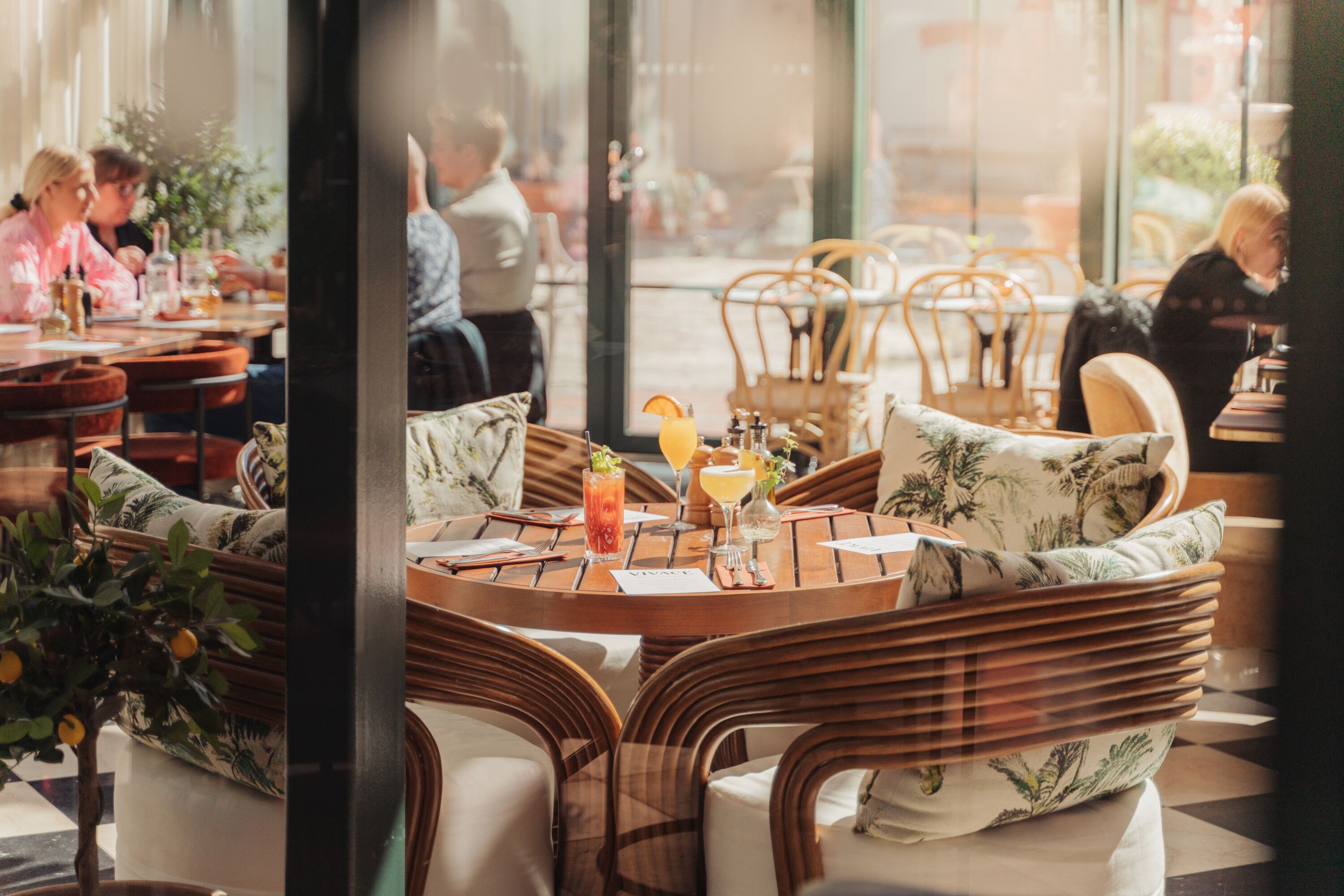 A restaurant with wicker furniture and a glass partition.
