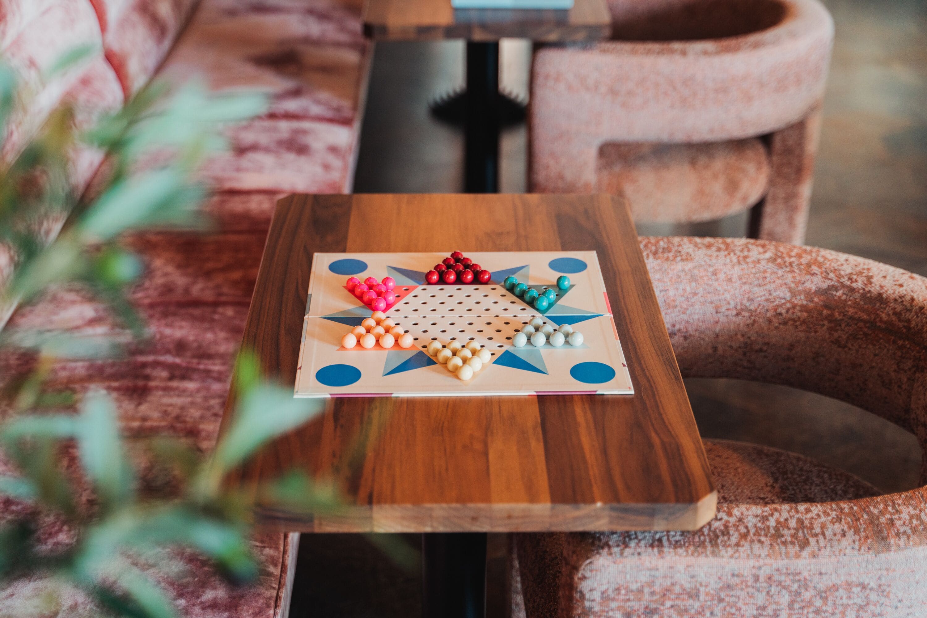 A wooden table with a board game featuring multicolored pieces.