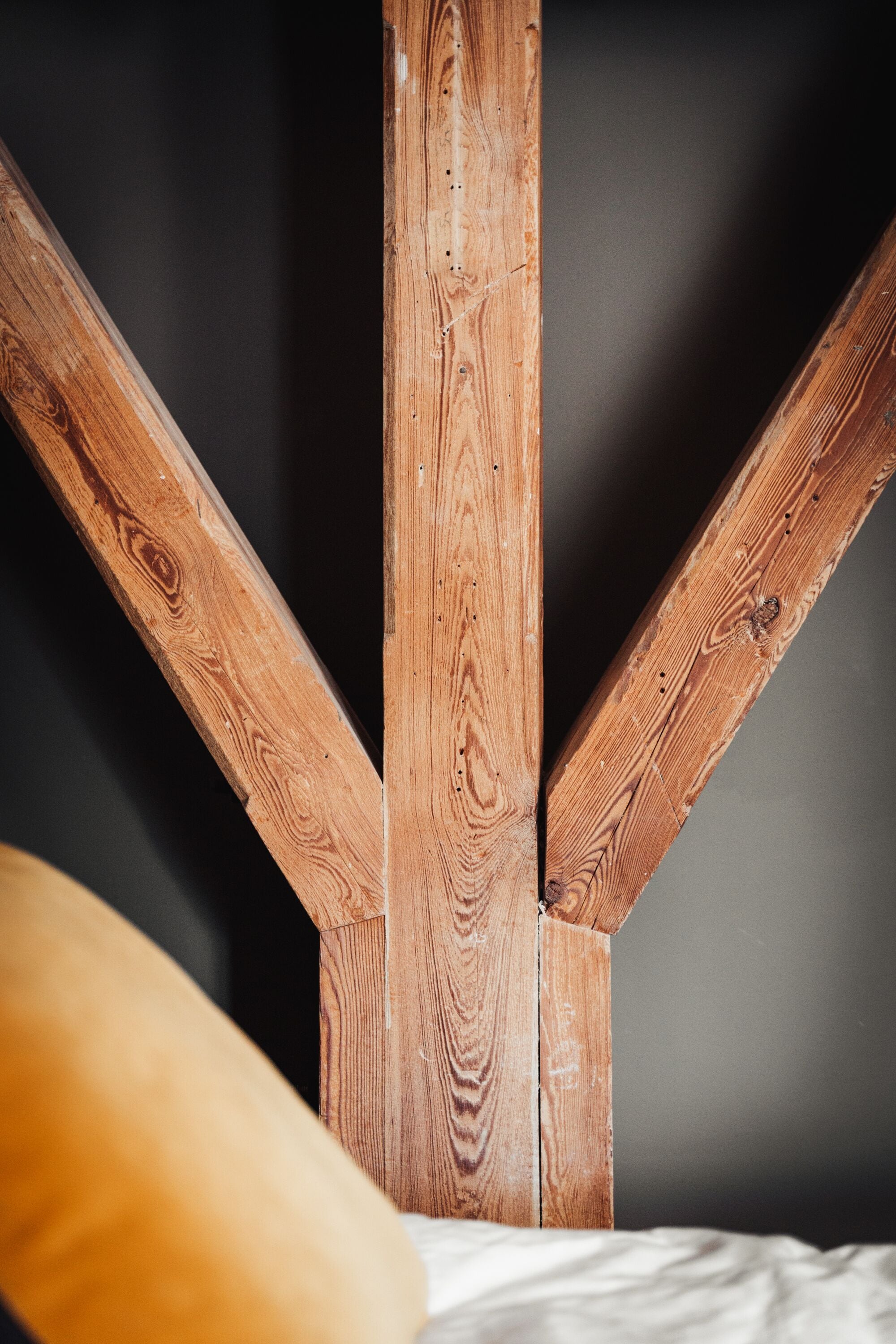 A wooden beam structure supporting a bed with a white mattress.